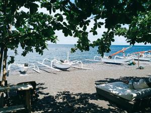 a beach with boats on the sand and the water at Solaluna Beach Homestay in Amed