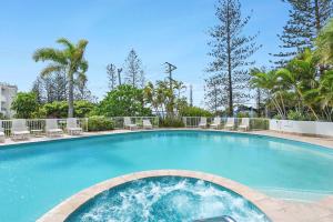 une grande piscine avec des chaises et des arbres dans l'établissement Crystal Bay On The Broadwater, à Gold Coast