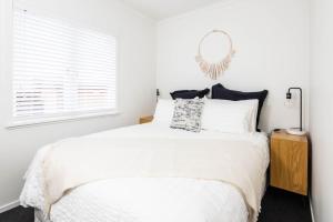 - une chambre blanche avec un grand lit et un miroir dans l'établissement Awesome Beach House on Oceanview Road, à Mount Maunganui