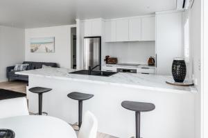芒格努伊山的住宿－Awesome Beach House on Oceanview Road，厨房配有白色橱柜和带凳子的台面