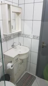 a white bathroom with a sink and a mirror at Apartamento 2 quartos em Torres-RS in Torres +15 photos