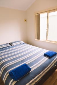 a bed with two blue towels on it in a room at Port Gregory Caravan Park in Gregory