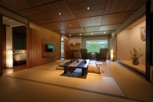 uma sala de estar com uma mesa e um quarto em Oushuku Onsen Choeikan em Shizukuishi