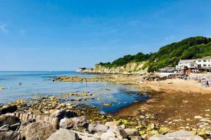a beach with rocks and people in the water at Seascape Cottage, Ventnor in Ventnor