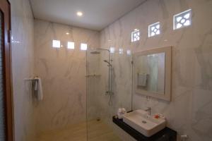 a bathroom with a shower and a sink and a mirror at Juada Garden in Seminyak