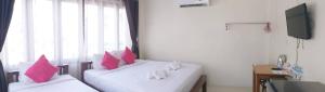 a room with two beds with pink pillows and a window at Ban Mae Boonthong in Lampang