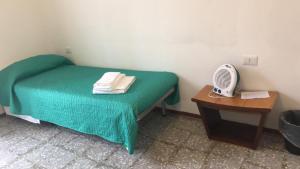 a small room with a green bed and a table with a fan at Castellaneta Short Term -Low cost in Castellaneta