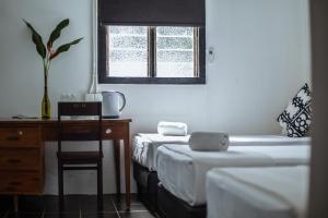 a room with three beds and a desk and a window at The Marian Boutique Lodging House in Kuching