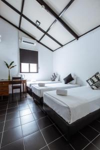 a room with three beds and a table and a chair at The Marian Boutique Lodging House in Kuching
