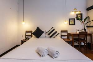 1 dormitorio con 1 cama blanca grande y 2 toallas en The Marian Boutique Lodging House en Kuching