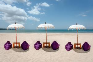 un grupo de sillas y sombrillas púrpuras en una playa en Kedonganan Beach Villas, en Jimbaran