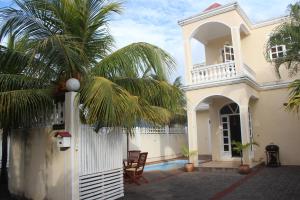 a white house with a palm tree in front of it at EHolidays Villa in Pereybere