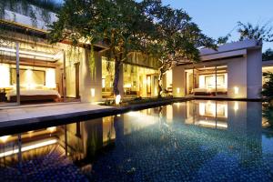 a swimming pool in front of a house at Kedonganan Beach Villas in Jimbaran