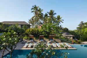 a resort with a swimming pool and lounge chairs at Nirjhara in Tabanan