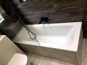 a white bath tub in a bathroom with a toilet at Double Bedroom, Kings Lynn, New Renovated Bathroom in King's Lynn