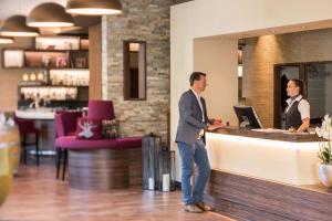 a man and a woman standing at a counter at Hotel Peterhof - urban lifestyle Kempten in Kempten