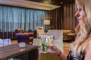 Hotel Peterhof - urban lifestyle Kempten في كمبتن: امرأة تجلس على طاولة تحمل الشراب
