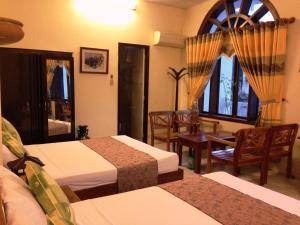 a hotel room with two beds and a table and chairs at Dong Loi Hotel in Hue