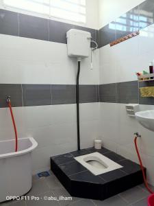 a bathroom with a toilet with a black floor at Ilham Imani Homestay in Kampung Gurun +8 photos