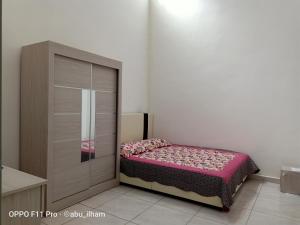 a bedroom with a bed with pink sheets on it at Ilham Imani Homestay in Kampung Gurun