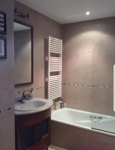 bagno con vasca, lavandino e specchio di Coqueto apartamento en Las margas golf a Sabiñánigo