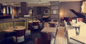 een restaurant met tafels en stoelen en een piano bij The Tontine Hotel in Greenock