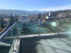 a glass balcony with a view of a city at Ferienwohnung Kaiserpanorama in Krumpendorf am Wörthersee