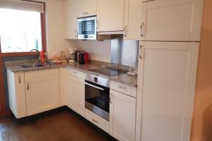 La cuisine est équipée de placards blancs, d'un évier et d'un réfrigérateur. dans l'établissement Ferienwohnung Resort Walensee 98 - Seehöckli, à Quarten