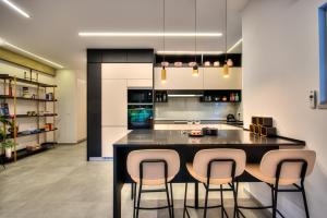 een keuken met een zwart eiland met drie barkrukken bij hovevei tsion 41 in Tel Aviv