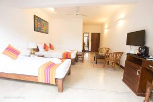 Jaffna Heritage Hotel في جافنا: غرفة فندقية بسريرين وتلفزيون بشاشة مسطحة