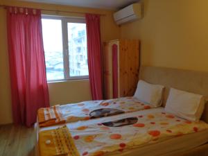 a bedroom with a bed with a floweridered comforter and a window at Apartment Moni 2 in Veliko Tŭrnovo