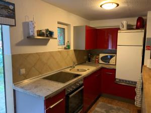 a kitchen with red cabinets and a sink and a refrigerator at Bungalow am Wassergrundstück in Wendisch Rietz