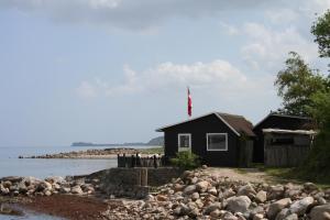 a black house on the shore of a body of water at Loff Holiday Houses in Aabenraa