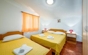 two beds in a room with yellow sheets at ALEKS house with apartments in Umag