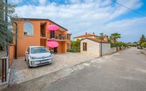 a car parked in front of a house with pink umbrellas at ALEKS house with apartments in Umag