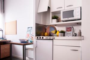 Una cocina con gabinetes blancos y un microondas. en Residencia Resa Tomás Alfaro Fournier, en Vitoria-Gasteiz