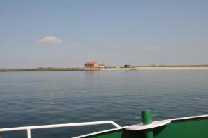 un barco en el agua con una casa en la distancia en Residentie Oosterschelde, en Sint Philipsland