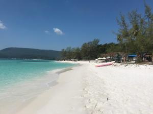 a white beach with a pink boat on it at Soksan Natura Beach in Koh Rong Island