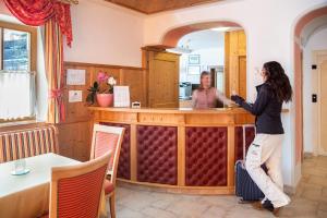 a woman standing at a bar in a restaurant at Hotel Gran Fanes in Corvara in Badia