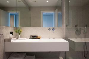 a bathroom with a large white sink and a mirror at Skiathos Palace Hotel in Koukounaries