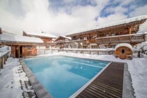 a house with a swimming pool in the snow at Les Loges Blanches Megève in Megève