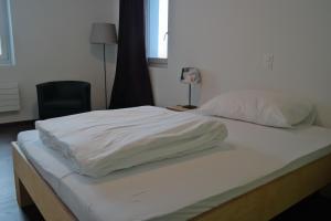 uma grande cama branca em um quarto com uma cadeira em Gasthaus zum Ochsen em Grosswangen