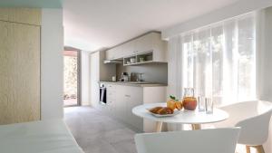 a white kitchen with a table with fruit on it at Résidence Mobydick in Porto-Vecchio