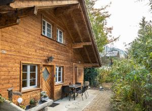 une maison en bois avec une table et des chaises à l'extérieur dans l'établissement Chalet Wäschhüsli near Interlaken, Grindelwald and Lauterbrunnen, à Gsteigwiler