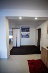 een lege kamer met een deur en een rood tapijt bij City Center Apartments in Pirot