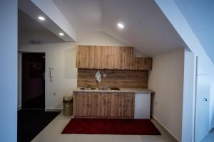 een keuken met houten kasten en een wastafel bij City Center Apartments in Pirot