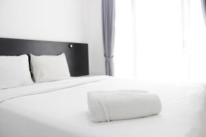 białe łóżko z białymi poduszkami i oknem w obiekcie Stylish Studio Room Grand Asia Afrika Apartment By Travelio w mieście Bandung