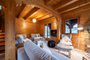 Chalet Doux Abri Morzine - by EMERALD STAY في مورزين: غرفة معيشة مع أريكة وكراسي في كابينة خشب