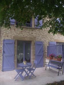 una mesa de picnic y un banco frente a un edificio con puertas azules en Domaine des cigales, chambre d'hôtes, en Saint-Martin-dʼAoût