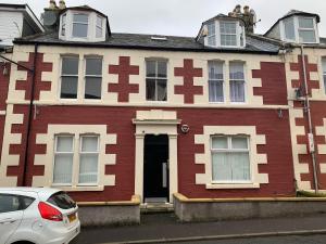 a red and white house with a white car parked in front at 105 Nelson Street in Largs